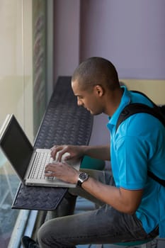 Side profile of a young man using a laptop in a cafe