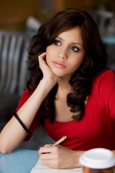 Close-up of a young woman writing on a sheet of paper