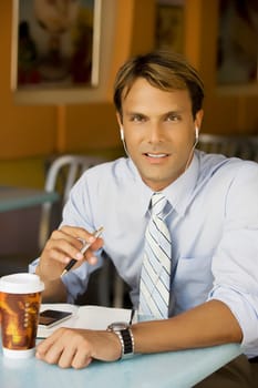 Portrait of a businessman listening to an MP3 player in a cafe