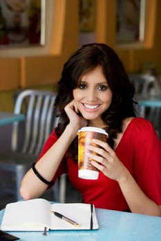 Portrait of a young woman holding a cup of cold drink and smiling