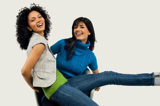 Portrait of a young woman sitting in an armchair with her friend sitting on her lap