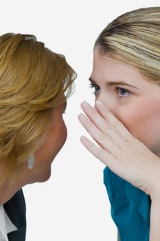 Close-up of a businesswoman whispering into another businesswoman's ear