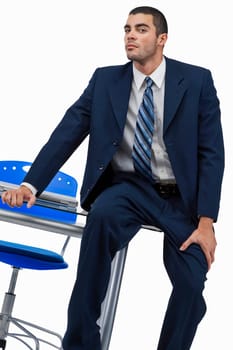 Portrait of a businessman sitting on a desk in an office