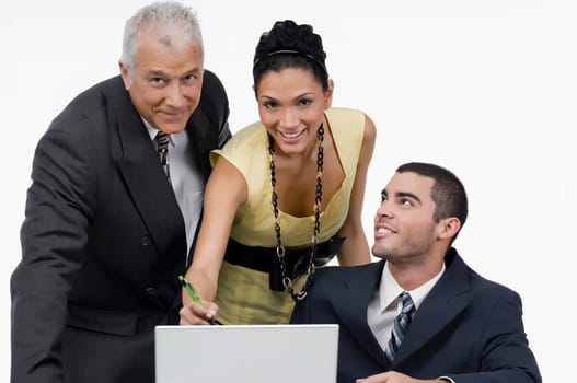 Two businessmen and a businesswoman discussing on a laptop in an office