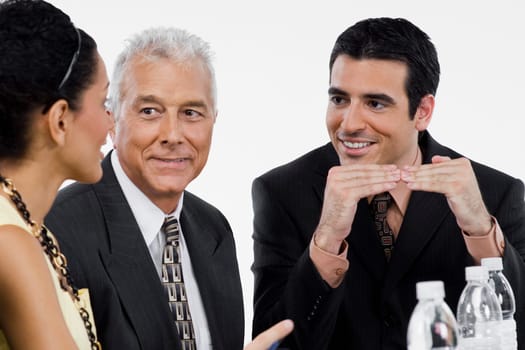Two businessmen and a businesswoman at a meeting in a conference room