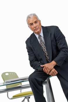 Portrait of a businessman sitting on a desk in an office