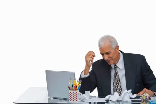 Businessman sitting at a desk with crumpled paper on the desk