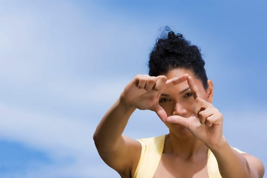 Portrait of a young woman making a finger frame in front of her face