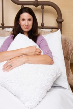 Portrait of a mid adult woman hugging a cushion and smirking