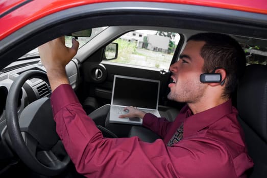 Side profile of a businessman sitting in a car and using a laptop