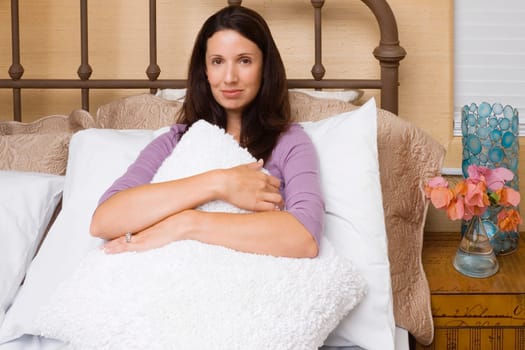 Portrait of a mid adult woman hugging a cushion and smirking