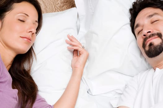 High angle view of a mid adult couple sleeping on the bed
