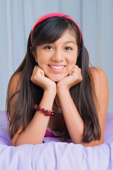 Portrait of a teenage girl lying on the bed and smiling