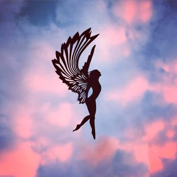 girl angel with wings made of paper. figurine against the sky. figurines carved from paper in a photo of the sky.