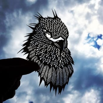 Animal figurines carved from paper in a photo of the sky. Paper-cut eagle figurine against the sky.