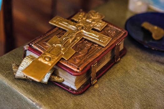 an old bible with a lock on the binding and a cross is on the book.