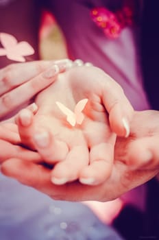 Paper butterfly in the hands of a couple. Newlyweds.