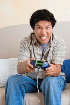 Close-up of a young man playing video game and smiling