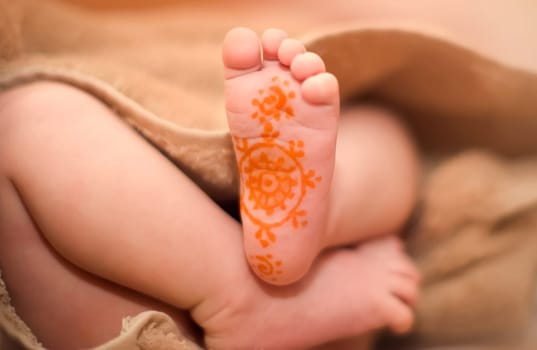 The baby's legs are from under the blanket. On the leg painted a pattern marker.