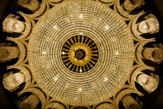 A view from the bottom up to a symmetrical beautiful chandelier. A big beautiful lust on a lot of light bulbs.