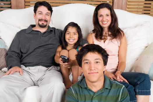Portrait of a mid adult couple watching television with their son and daughter
