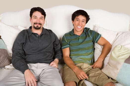 Portrait of a mid adult man and his son sitting on a couch and smiling