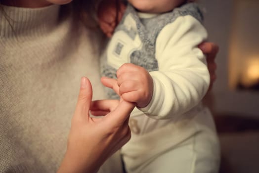 The child grabbed his mother's finger. The mother is holding the child in her arms.