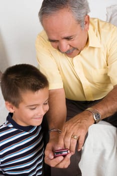 Close-up of a senior man showing a mobile phone to his grandson