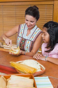 Mid adult woman preparing bread with her daughter in the kitchen