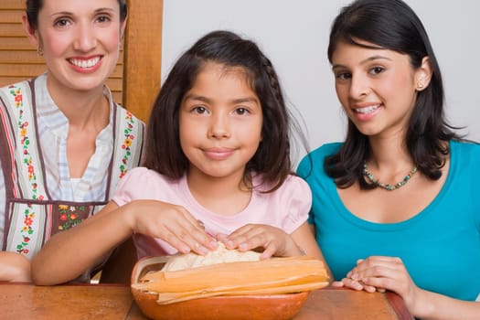 Portrait of a girl preparing bread with her mother and sister in the kitchen
