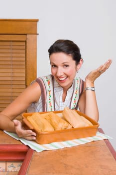 Portrait of a mid adult woman laughing with a tray of breads in the kitchen