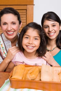 Portrait of a mid adult woman and her two daughters smiling with a tray of breads in the kitchen