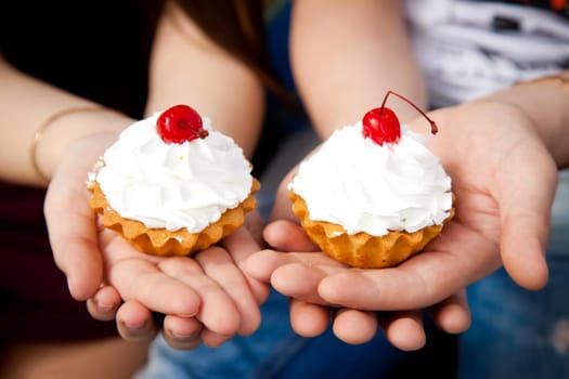 cupcakes with cream. Two cherry cakes on top. Cake in hand