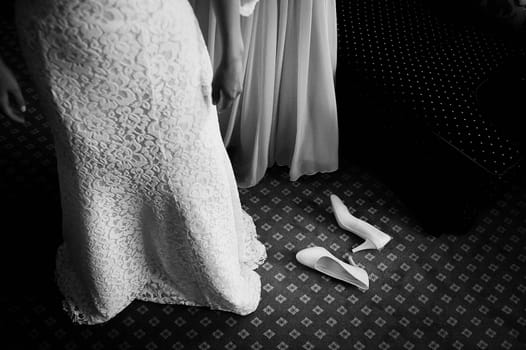 Bride in dress, shoes on the floor. The bride is dressed.