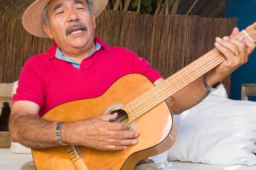 Close-up of a senior man playing a guitar and singing