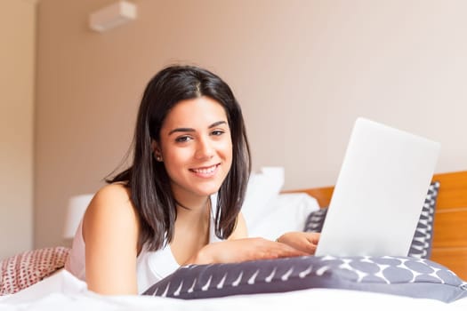 Young woman relaxing with her computer in bed