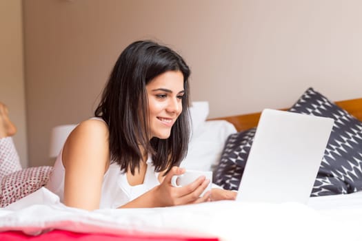 Young woman relaxing with her computer in bed