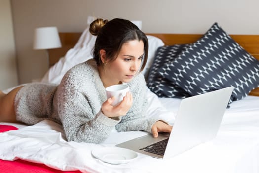Young woman relaxing with her computer in bed