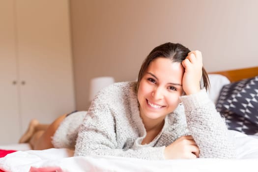 Young woman relaxing with her computer in bed