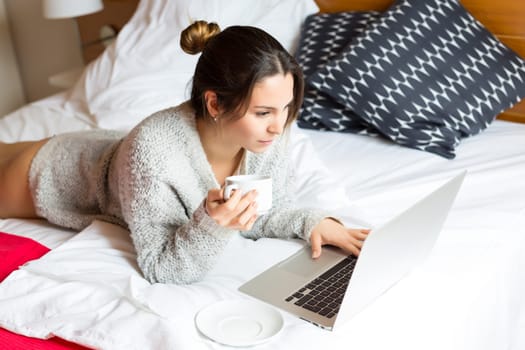 Young woman relaxing with her computer in bed
