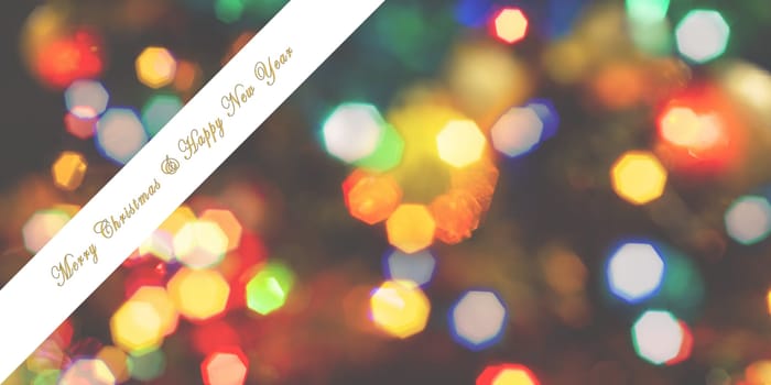 Merry Christmas and Happy New Year greeting card, blurred background of the twinkling lights of the Christmas tree. Greeting card background.