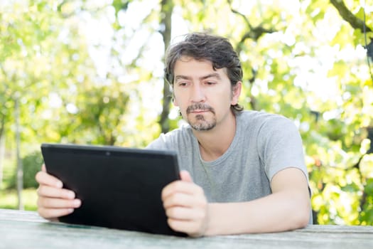 Young man relaxing with a tablet computer at a garden