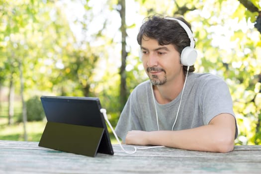 Young man relaxing with a tablet computer at a garden