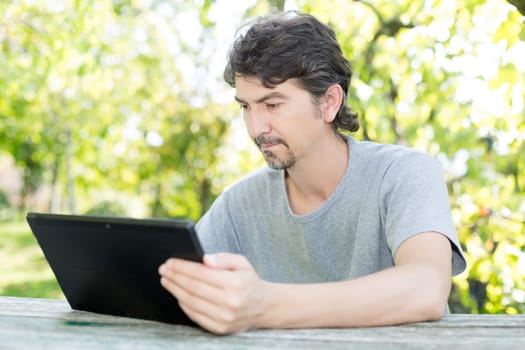 Young man relaxing with a tablet computer at a garden