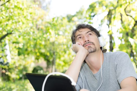Young man relaxing with a tablet computer at a garden