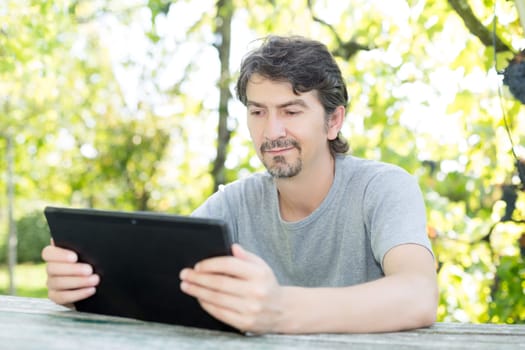 Young man relaxing with a tablet computer at a garden