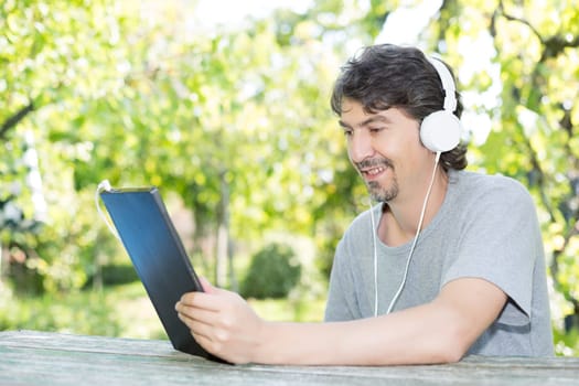 Young man relaxing with a tablet computer at a garden