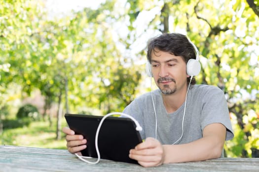 Young man relaxing with a touchscreen computer at a garden