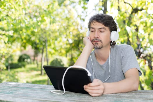 Young man relaxing with a tablet computer at a garden