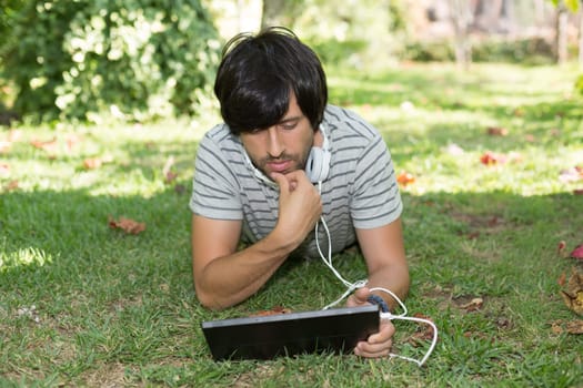 Young man relaxing with a tablet computer at a garden